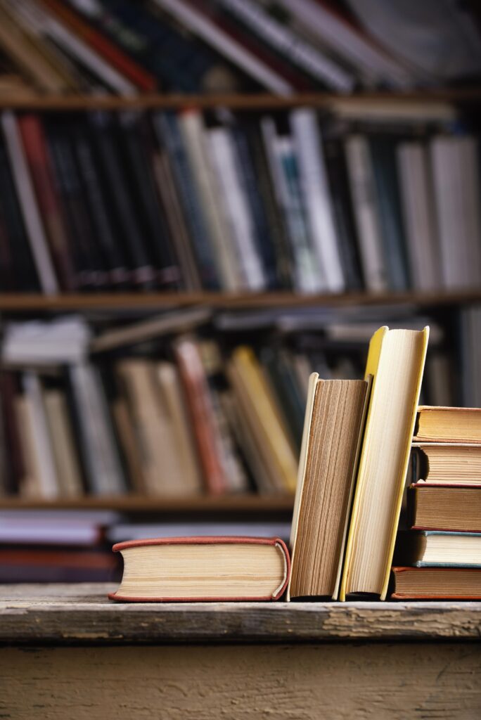 Widok książek w twardej oprawie, na tle biblioteki z książkami
